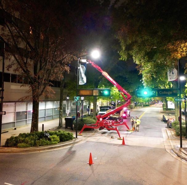 Worker in spider lift trimming tops of trees